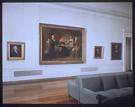 The image depicts a room with classical-style white walls adorned by several framed paintings, including one large painting and three smaller ones. The central piece is an elaborate portrait featuring multiple figures seated around a table or chair in what appears to be a sophisticated gathering. In the upper left corner hangs another individual's portrait within its own frame. On both sides of this main artwork are two more portraits placed on different vertical surfaces, possibly on shelves or picture rails.

Below these artworks lies a simple green upholstered sofa with straight arms and clean lines, suggesting an early 20th-century design aesthetic. The flooring is wooden planks painted white to complement the walls' color scheme. To the left of this scene can be seen part of what appears to be a large radiator or heating unit extending along the wall.

The overall setting evokes the atmosphere of an art museum gallery, specifically mentioning its association with the National Gallery of Art and highlighting it as being from George Washington room in ca. 1920-ca. 1950 era. The image is credited to Horydczak, likely a photographer or creator associated with this historical documentation.

The URL provided at the bottom suggests that more information can be found on "https://images.loener.nl/horydczak," which may offer additional context about these artworks and their s [...]
