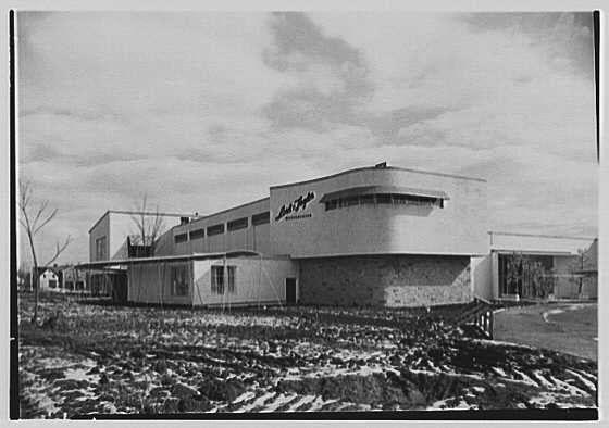 The image depicts an old black and white photograph of a commercial building, presumably taken around February 29th in the year 1948. The structure has a modernist design with clean lines, large windows, and flat surfaces. There is no visible activity or people present; it's just showcasing the exterior architecture against a partly cloudy sky.

In terms of context, this image appears to be associated with Lord & Taylor business in Westchester as per additional information provided (Lord & Taylor, business in Westchester). The photograph was taken by Gottschalks-Schleisner Inc., which suggests that it might have been used for architectural documentation or promotional purposes. One negative from the series is mentioned to measure 5x7 inches and can be found on a specific URL.

From this description alone, one may infer potential historical significance of the building's design as an example of modern architecture during World War II era in Westchester area - but it could also have been used for different purposes such as showcasing new developments or business establishments.