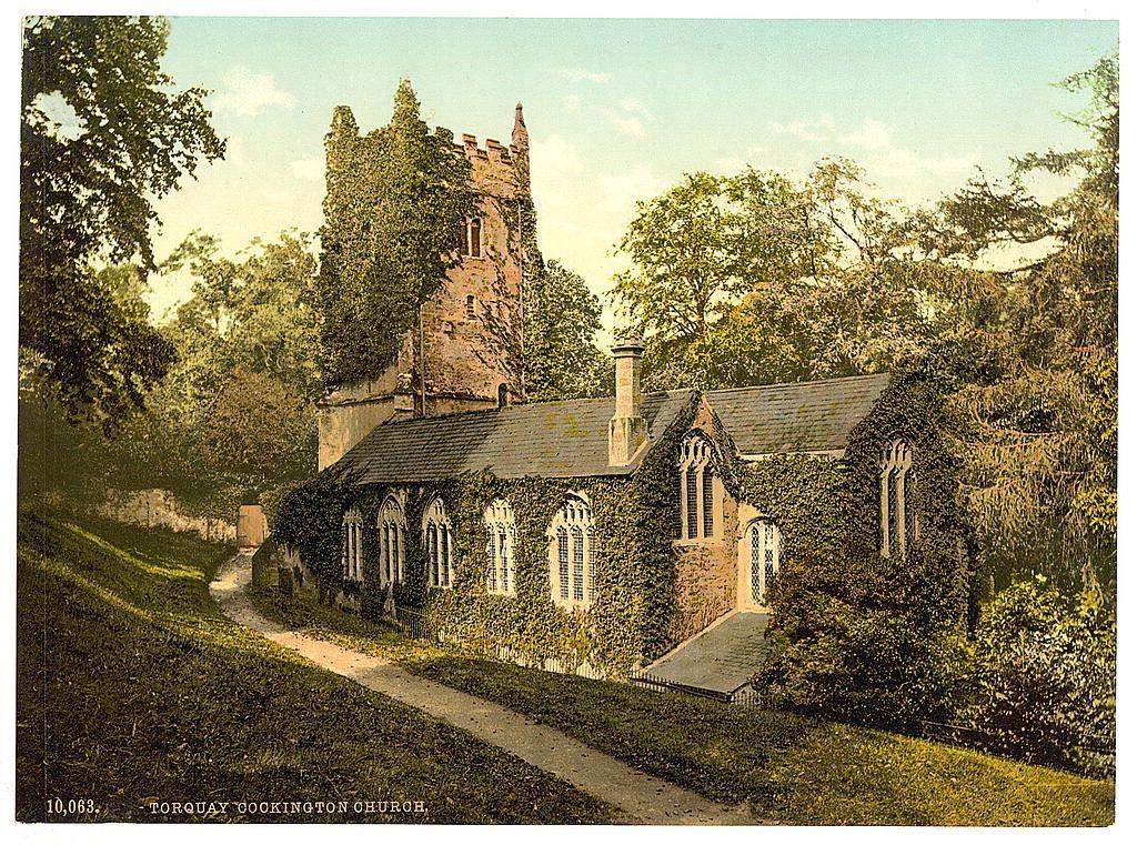The image depicts a picturesque and old English church, specifically identified as "Torquay Cockington Church" with the reference number 10,063. The scene is set in what appears to be an early part of the last century based on its style. It's likely that this photo was taken around the turn of the twentieth century, given the vintage appearance and coloration.

The church building exhibits traditional English architectural features such as stone construction with ivy growing over parts of it which gives a sense of age and historic preservation. There is an old tower attached to one side of the structure, suggesting medieval influences in its design. The surrounding area is lushly green with trees and shrubs that indicate this photograph was likely taken during spring or summer.

A pathway leads up to the church from where we are viewing it; on closer inspection, a slight incline can be seen leading into the entrance which may imply an upward climb before reaching the door. It's painted in earthy tones of greens and browns with hints of yellowish hues possibly due to sunlight filtering through trees above.

Overall, this image presents a tranquil rural scene that embodies historical charm and suggests it could have been used as postcard art during its time for tourists or locals alike to remember their visits by.