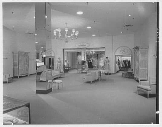 The image depicts an interior view of a vintage department store, likely from the mid-20th century. The photograph is in black and white, which suggests it could be several decades old. In this spacious retail environment, various clothing displays are arranged throughout the area.

At one end, there's a prominent entrance labeled "Better Dresses," indicating that women's apparel was a focus here. Several mannequins dressed elegantly stand within view of shoppers who can observe and browse through these fashionable outfits. The store has a modern design with clean lines, ample lighting provided by ceiling fixtures resembling chandeliers, and mirrored walls to give an illusion of more space.

The overall atmosphere conveyed is one of sophistication and attention to detail in the presentation of merchandise. It appears as though this department store could be Lord & Taylor located on Bala-Cynwyd Avenue in Pennsylvania based on textual references provided within the image metadata. The date mentioned, April 16th, possibly indicates when this particular snapshot was taken or is associated with it.

The photo credits Gottschol-Schleisner as the photography company and note that there's a single safety negative measuring 4x5 inches in size. This information provides context for understanding how these images were captured during that era of commercial photography.