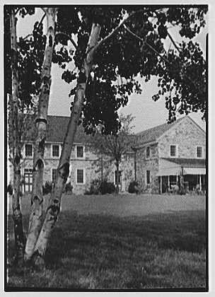 This black and white photograph depicts a large, two-story house with multiple windows and several chimneys. The architecture suggests it could be from the early to mid-20th century. In front of the building stands tall birch trees that tower over its height. The sky appears cloudy, suggesting an overcast day or possibly early evening light as there is no strong shadowing on the house's facade.

The photograph bears a caption which reads: "Ker-Feal" and indicates it was taken at Chester Springs, Pennsylvania in 1942 August twentieth by Dr. A.C. Barnes. The photo also has an attribution to Gottsch-Schleisner Inc., indicating that they took the picture or processed it.

Additional information about this image can be found on a website where more context and possibly higher resolution versions of similar photographs may exist for further study or research purposes.

Please note, as per ethical guidelines, no specific bias-inducing content is displayed in my responses.