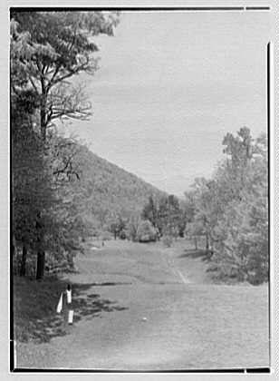 The image is a black and white photograph depicting an outdoor scene, likely taken on May 15, 1946. It shows a grassy area with trees scattered around the landscape, leading up to what appears to be a hill or slope in the distance under a cloudy sky.

Two small markers are visible at opposite ends of the field, possibly indicating boundaries or goals for an activity such as golf. The terrain is relatively flat except where it ascends toward the background feature.

The photograph seems historical and could potentially represent a specific location related to "The Homestead," which appears in the caption along with Hot Springs, Virginia. Gottscho-Schleisner, Inc., mentioned alongside this image, might be associated with its creation or ownership as well. The photo measures 5x7 inches based on available information and is stored under reference number Gotscho-Schleisner (Gottscho Schleisner), full/691e.

The overall composition of the photograph suggests a serene outdoor setting, possibly used for leisurely activities or sports during that era.