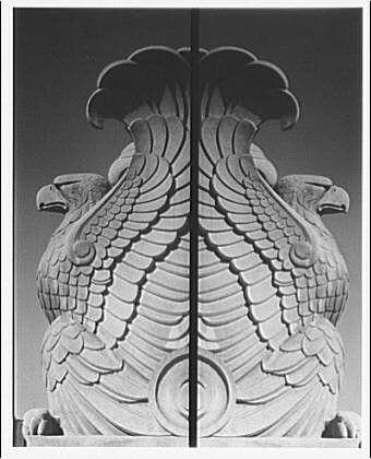 The image depicts a large, intricately carved stone eagle with its wings spread wide open on top of the National Archives Building. The sculpture is symmetrical and appears to be part of an ornate decorative element at either end of what could possibly be a doorway or entranceway.
This particular photograph was taken around 1920-1950, according to additional information found in various archives related to Horydczak, approximately from the years 1890 to 1971. The sculptor's name is mentioned as "Horydczak," and it can be seen on one of his works.
The photograph has a black-and-white tone, which gives it an aged appearance, indicative of its historical context or perhaps due to the quality of film used during that time period for documentation purposes at government institutions. The dimensions provided suggest this image was captured using large-format photography equipment typically employed in official archival records from before digital imaging became prevalent.
The eagle's craftsmanship is remarkable; each feather appears meticulously carved with precision, highlighting the skill and attention given by Horydczak to his workmanship during that era of American architecture and design. The contrast between light and shadow within the stone adds depth and dimensionality, emphasizing its three-dimensional form and making it an impressive visual representation.
In summary, [...]
