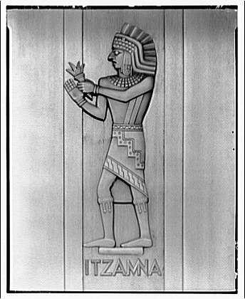 The image shows a relief of Itzamna, an ancient Mayan deity associated with writing and learning. The figure is depicted standing upright on one leg, with the other extended to reveal his feet adorned in intricate patterns. He wears elaborate clothing including a feathered headdress, a shawl over his shoulders, and trousers held up by sashes. In his left hand, which is raised towards his chest, he holds what appears to be an object or offering. The name "ITZAMA" is inscribed below the figure in bold letters.
This relief was likely part of a decorative element on a door within the Library of Congress building's annex during its time between approximately 1920 and 1950. The photograph, taken by Theodore Horydczak (approx. 1890-1971), is preserved as one negative measuring 8 x 10 inches in safety film format.
The image provides insight into the influence of Mayan culture on American institutions during that period and highlights the artistic representation of religious figures from ancient Mesoamerican civilizations within modern architecture and design.