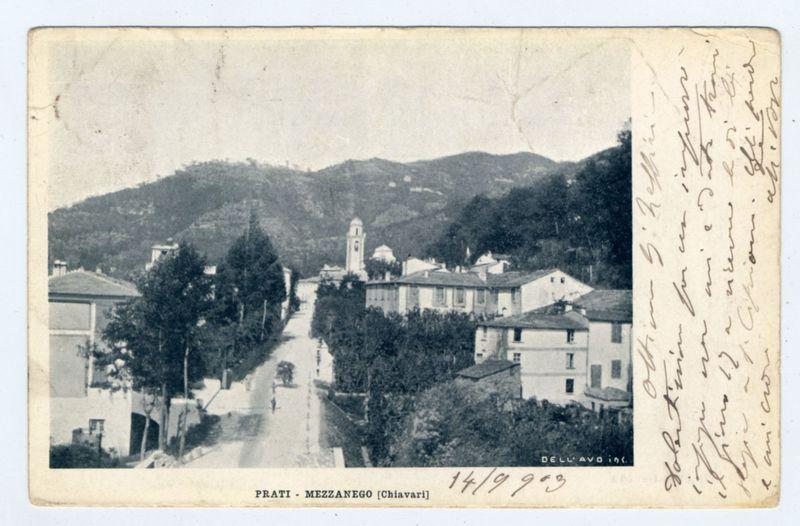 The image depicts an old postcard showing a panoramic view of a town, labeled "PRATI - MEZZANEGO [Chivari]" with the date inscribed as "14/9 953". The scene is set in what appears to be early-to-mid-20th-century Italy. In the foreground, there's a paved street that leads toward an open area flanked by buildings and trees on either side. Architectural styles suggest European influences with modest two-story residential structures lining both sides of the road.

In the mid-ground, several white or light-colored houses stand out against darker rooftops in the background. The most prominent feature is a bell tower rising above other buildings to the right center of the image, suggesting it may be part of a church or civic building. To its left stands another tall structure that could also serve as an observation point.

The background reveals rolling hills with sparse vegetation and what seems like residential development spread across them. The sky appears overcast, casting even lighting on the scene without strong shadows. Handwritten notes in cursive script adorn the upper right corner of the postcard; however, they are not clear enough to be read or transcribed.

The overall impression is that of a quiet town nestled within its natural surroundings and perhaps captured during a moment when life was slower-paced compared to modern times.