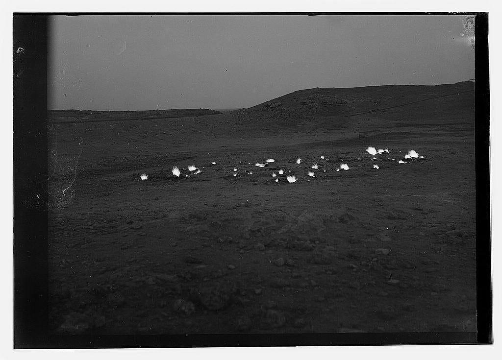 The image is a black and white photograph depicting an open, barren landscape with several bright flames scattered across the ground. The setting appears to be during dusk or dawn as there's limited light in the sky above.

In the distance, gently rolling hills can be seen against the horizon under what seems like overcast conditions. There are no visible structures or people within this scene; it is a desolate environment that stretches far into the background.

This photograph captures something unusual for its time and place: "perpetual fires caused by constant escape of natural gas." These fires, referred to as oil wells in some parts, were particularly prominent during the early 20th century. In this case, they are located near Kirkuk District, which was under control of the Iraq Petroleum Company at that time.

The photograph is labeled "American Colony (Jerusalem). Photo Department," indicating it may have been part of a collection or used for documentation purposes related to colonial activities in Jerusalem during its American period. The image also carries historical significance as it documents an environmental phenomenon caused by natural gas escapes, which played a role in the broader context of energy extraction and geopolitical interests at that time.

The reference "1 negative : nitrate" suggests that this photograph is one out of many captured on photogra [...]