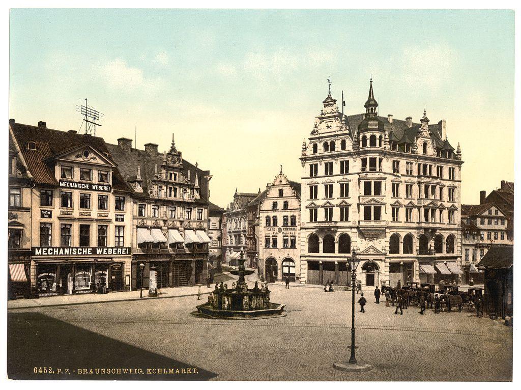 The image depicts a historical European square, likely from the late 19th or early 20th century based on architectural styles and clothing of people visible in the photo. The setting appears to be Braunschweig (Braunswiek), Germany's Kohlmarkt ("Coal Market") as indicated by text at the bottom left corner which reads "Mechanische Weberei" - a textile company likely located there, with "Kohlmarkt" inscribed above it on another building. The buildings are ornate and multi-storied, indicative of commercial or institutional architecture common in European cities during this era.

In the center foreground is an elegant fountain surrounded by cobblestone paving, suggesting that Kohlmarkt was a significant public space for residents to gather. A horse-drawn carriage with several figures stands near the fountain, conveying a sense of daily life and commerce at the time. The absence of modern vehicles or technology further situates this scene in the past.

The image has an aged quality typical of early colorized prints from that period; it's likely produced through photochrom printing technique which was popular for creating images using colored photographic processes before widespread use of black-and-white film photography became more prevalent. This method allowed a wider audience to appreciate cityscapes and public spaces in vibrant colors, capturing the visual vibrancy often  [...]