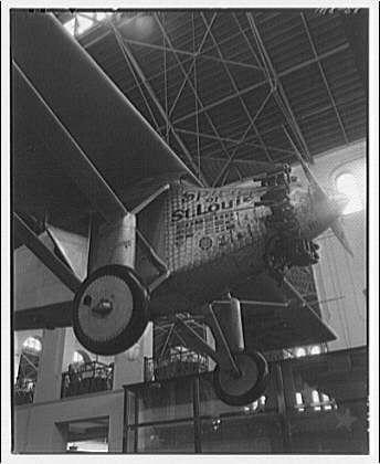 The image displays a historical airplane known as the "Spirit of St. Louis" suspended from an indoor structure, likely within a museum setting. The aircraft is prominently featured in black and white tones, highlighting its vintage design with distinct propellers on each wing. Text visible on the side of the plane includes "Missouri," indicating it may have been named after or sponsored by Missouri during that period.

In addition to this photograph's depiction, further information about this airplane can be found within Smithsonian Institution interiors, specifically in a collection from approximately 1920 to around 1950. The photographer is identified as Horydczak (likely Theodore), with an estimated lifespan of circa 1890-1971.

The photograph captures the essence of early aviation history and showcases the "Spirit of St. Louis" in its preserved state, which adds to our understanding of the aircraft's significance during that era.