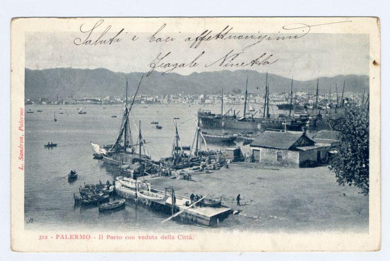 The image depicts a historic postcard of Palermo's harbor, showcasing several sailing ships and smaller boats moored at the dock. The scene is bustling with maritime activity, including both large cargo vessels and smaller fishing crafts. In the background, hills or mountains are visible across the water, under an overcast sky.

Handwritten Italian script in cursive on top of the postcard reads "Salute e baci affettuosoim" followed by a signature that appears to be Grazie Stella. Below this text is additional information stating "Palermo - Il Porto con veduta della Città." The bottom left corner bears the name 'L. Sandron, Palermo' which likely indicates the photographer or owner of the postcard.

The overall tone and details suggest an early 20th-century setting for this image, capturing a moment in time from Palermo's vibrant harbor life.