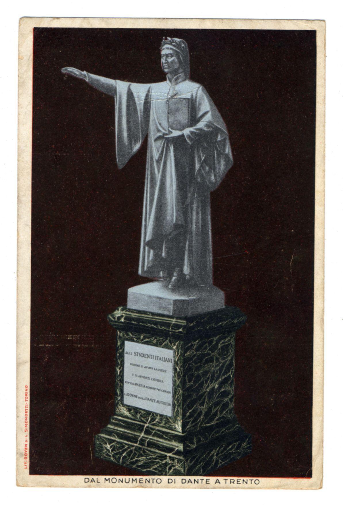 The image features a monochrome photograph of a statue, presumably from an old postcard. The statue portrays what appears to be Dante Alighieri in his iconic robes and pointed cap associated with the 14th-century Italian poet known for works such as "La Divina Commedia." He is depicted mid-gesture with one arm extended outward and palm upraised, a pose often used symbolically or theatrically. The statue stands on an ornate pedestal that has inscriptions in Latin at its base.

The backdrop of the image is plain dark brown, which highlights the figure of Dante prominently against it. At the bottom right corner of the photograph, there's text indicating "DAL MONUMENTO DI DANTE A TRENTO," suggesting a connection to Trento, Italy—perhaps referring to the monument dedicated to Dante in that city.

The overall condition and style suggest this could be an antique or vintage postcard capturing historical significance. The presence of Italian inscriptions points towards an Italian-speaking context for the origin of the image.