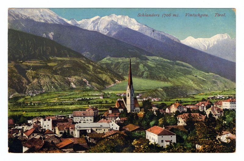 This image is a vibrant vintage postcard showcasing the picturesque landscape of Schlanders in Vintschgau, Tirol. The scene prominently features an imposing church with a tall spire at its center, surrounded by quaint houses and lush greenery indicative of rural life. Behind this charming village setting lies a stunning backdrop of majestic snow-capped mountains, which contrast sharply against a clear blue sky. The verdant slopes gently descend into rolling hills adorned with what appears to be farmland or vineyards, highlighting the agricultural aspect of the region.

The postcard's top right corner bears text that reads "Schlanders (706 m.), Vintschgar. Tirol," providing geographical context and elevation information for Schlanders, which is situated at an altitude of 706 meters in South Tyrol, Italy. The overall composition captures a serene yet idyllic representation of this Alpine community during what seems to be the golden age of postcard photography.

The image conveys not just visual beauty but also hints at historical and cultural aspects, as indicated by its vintage nature and informative text, suggesting that it was used for promoting tourism or preserving memories. The website mentioned in the description (https://images.loener.nl/FerroCandilera/full/6730/6730ad9089b10e7a26b72f52.jpg) likely provides further historical and cultural details about this location [...]