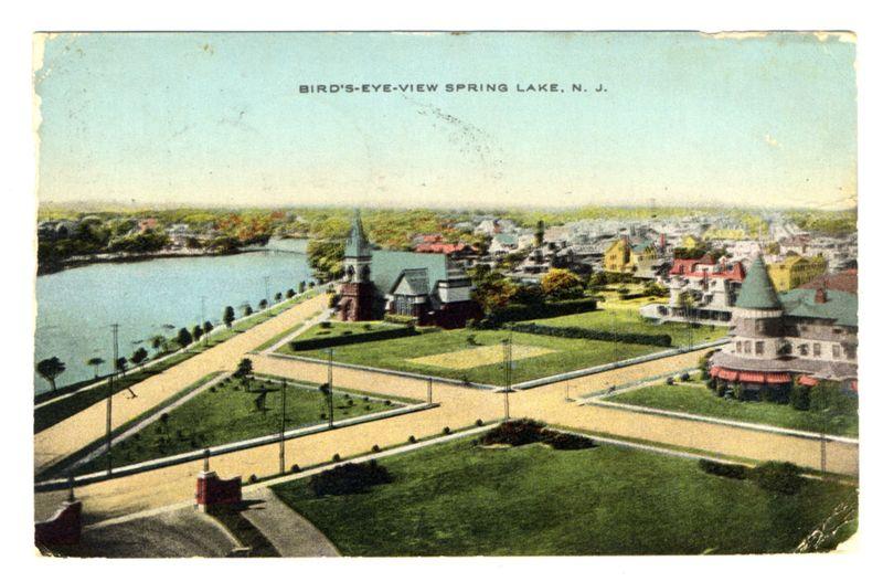 This image is a vintage postcard depicting Spring Lake, New Jersey. The view shows a bird's-eye perspective of the town with its central area prominently featuring several distinctive buildings and structures surrounded by orderly streets lined with trees and manicured lawns. On one side of the frame, there's an expansive body of water that appears to be a lake or river extending into the distance where it meets rolling hills in varying shades of green, suggesting rural surroundings.

The architecture includes what seems like early 20th-century residential homes painted in bright colors and larger structures with gabled roofs. The central feature is a large building with a prominent steeple that could be a church or town hall, flanked by other buildings including what looks like the main street leading to these key landmarks.

The image has an aged look typical of early postcards from around 1905-1920s, indicated by its coloration and slight damage at the edges. There are no people visible in this snapshot; instead, it captures a serene moment showcasing Spring Lake's urban planning and natural beauty during that era.

Text on the image reads "BIRD'S-EYE-VIEW SPRING LAKE N.J.", providing context to both location and perspective of the scene depicted within the frame. The text is part of postcard design intended for postal use, often used in promotional or personal corresp [...]