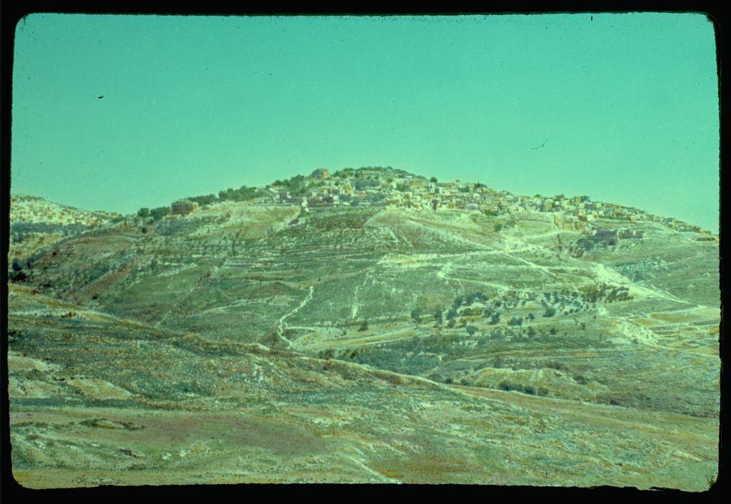The image shows a hilly landscape with multiple terraced levels and clusters of buildings, indicative of human habitation. The terrain appears arid or semi-arid, featuring sparse vegetation in some areas but more concentrated plant life on others. A clear sky can be seen above the hills, hinting at dry weather conditions typical for such environments.

The photo is presented with a vintage look, characterized by its coloration and slight vignetting effect around the edges, suggesting that it may have been taken between 1950 and 1977 as mentioned in the caption. The photograph seems to be part of a collection from Matson Photo Service, known for their documentation work related to geographic regions.

"A city set on a hill cannot be hidden" (Matt. 5:14) is inscribed above this particular image, likely adding a contextual or metaphorical layer to understanding the scene depicted in the photograph. This biblical quote underscores themes of visibility and prominence within communities situated geographically high up, such as Safed mentioned in the caption.

Further information about this specific photo can be found in "Around the Sea of Galilee," which is potentially an associated publication that provides additional insights or background on the photographed area.