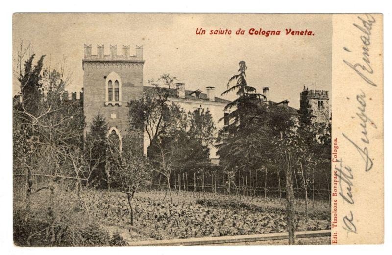 The image is a vintage postcard depicting an old architectural structure, presumably Colonna Veneta in Venice. The building has Gothic-style features such as pointed arch windows and crenellated battlements on top of the tower. It stands amidst trees that are likely to be evergreen given their conical shape, suggesting this may have been taken before deciduous trees became more prominent in gardens or were pruned for aesthetic reasons.

In front of the building is a garden with rows of crops and young plants being cultivated, indicating agricultural activity within what could otherwise appear as an estate. The overcast sky suggests it's either early morning or late afternoon light conditions typical during cooler seasons when such vegetation might be more prevalent in temperate climates.

The postcard bears handwriting on its right edge that seems to say "Ferioz Bonaparte - Colonia" followed by a signature, and the top of the card reads "Un saluto da Colonga Veneta," which translates from Italian as "A greeting from Venice." This suggests it is a personal note or message included with the postcard.

In terms of coloration, due to its age, the image has faded into shades of gray; however, original prints might have showcased more earthy tones. There's visible wear and tear on the paper indicating it’s quite old which could mean that this photograph dates back many decades  [...]