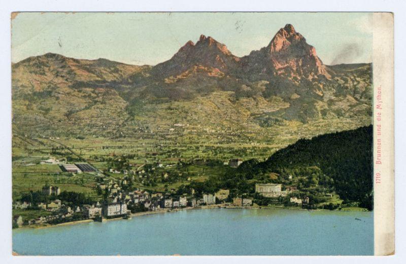 The image depicts a scenic view of Lake Lucerne with the iconic Horevstuhl mountains in the background. This vintage postcard appears to be from around 1910, as indicated by its aged and slightly worn condition on the edges. The town is nestled along the shoreline, showcasing various buildings including residential houses, larger estates or institutions, and a prominent church with distinctive architecture featuring spires.

The lake's waters reflect the blue sky above, which has a hint of pale yellow near the horizon due to sunlight diffusing through possibly misty air conditions typical in Swiss alpine regions. The surrounding landscape is dotted with agricultural fields that vary from shades of green indicating different types of crops or pastures. To the right side at the bottom corner, there's a text inscription "1719: Brunnens und die Mythen," which translates to "The springs and myths." This likely refers to mythological stories associated with Lake Lucerne.

Overall, this image captures not only the natural beauty of Switzerland but also hints at cultural elements through its mention of local legends.