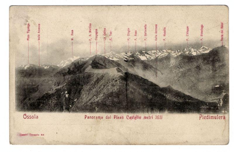 The image depicts a vintage postcard showing a panoramic view of mountain peaks. The mountains are labeled with various names, indicating they might be located in the Ossola region or Piedimulera area, as noted at the bottom right and left corners respectively. Notable peaks such as "M. Rosa," "P. Colma," "Cingolia," among others, are marked along the mountain ridges.

The mountains appear rugged with snow-capped summits in some areas, suggesting a high altitude or winter season when the photo was taken. The landscape is monochromatic except for red labels and text that provides names of peaks and locations like "Ossola" on top left corner and "Piedimulera" at bottom right.

At the center foreground, there's an inset photograph showing two individuals standing by a fence or gate with one person holding what appears to be a rifle. The attire suggests early 20th-century fashion, possibly indicating historical context of exploration or settlement in mountainous regions.

The postcar