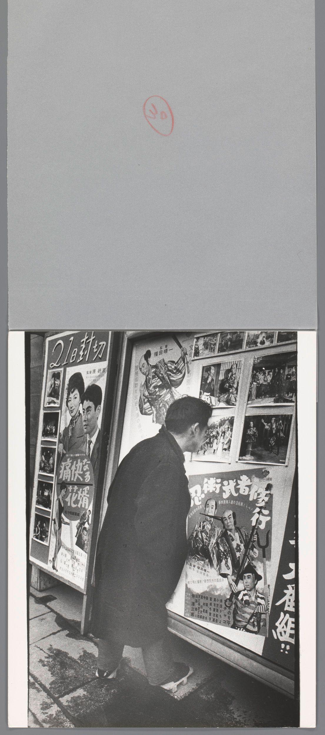 The image depicts a black and white photograph of an individual standing in front of a poster display. The person appears to be examining the posters closely, which are variously illustrated with images related to Japanese movies or events featuring actors and historical figures depicted as samurai warriors. Notably, there's text on some of these posters that is not legible due to image resolution constraints but suggests they might contain titles or descriptions in Asian script.

The scene captures a moment from the cultural life likely set during Japan’s post-World War II era, reflecting an interest in local cinema and history. The individual has dark hair visible at their head's edge, dressed in what seems like typical attire of that period with dark clothing. They are standing on a sidewalk beside a storefront or stall dedicated to these promotional posters.

The image is part of the collection from "Man kijkt naar een aankondiging van een samoeraifilm" (translated: Man looking at an announcement for a samurai film), taken by Ed van der Elsken, and dates back between 1959-60. The photograph conveys a candid snapshot of everyday life in Japan during that time frame through the lens of street culture photography.