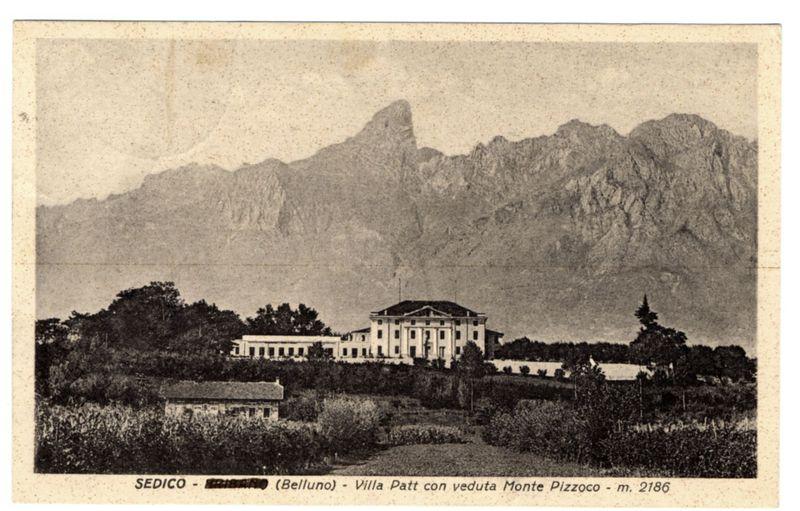 The image depicts a black and white photograph of an early 20th-century postcard featuring the Villa Patt with views of Monte Pizzocco in Sedico, Italy. The villa is situated amid lush greenery with expansive gardens in front of it. In the background stands imposingly large, rugged mountains that rise dramatically above the landscape, adding a sense of grandeur to the scene.

The sky appears overcast or sepia-toned due to the age and condition of the photograph, contributing to an overall vintage atmosphere. The image is marked with text at the bottom left corner indicating "Sedico - Villa Patt con veduta del Monte Pizzocco" along with a reference number "m. 2186". There's also additional mention that reads "(Belluno)" which could refer to Belluno province where Sedico and Monte Pizzocco are located.

This specific photograph seems part of a collection, perhaps documenting historical landmarks or significant locations in the region during its time as captured by Ferro Candilera.