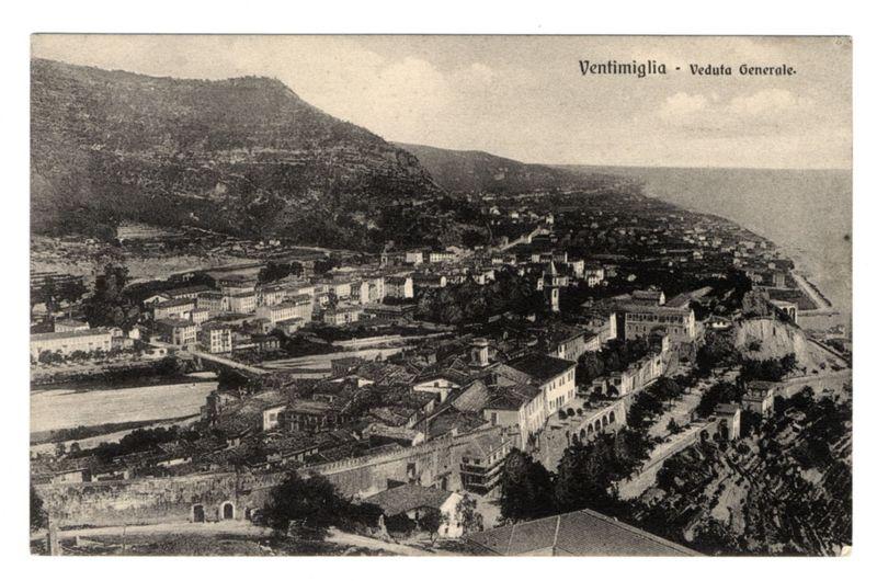 The provided image is a historical black and white photograph depicting the town of Ventimiglia, as seen from an elevated vantage point. This view showcases various architectural structures including buildings with distinct European-style roofs, indicating it could be located in Italy or another Mediterranean country. The scene displays a mix of urban development spread across terraced hills, blending residential areas with open spaces and greenery.

The photograph is labeled "Ventimiglia - Veduta Generale," which suggests that this image captures the general view of Ventimiglia from its topography to include both built environments and natural landscapes like rolling hills. The absence of modern infrastructure or vehicles implies an older time period, possibly in the late 19th or early 20th century.

This kind of imagery is often used for historical documentation, tourism promotion, or educational purposes regarding urban planning and architecture from past eras. It allows viewers