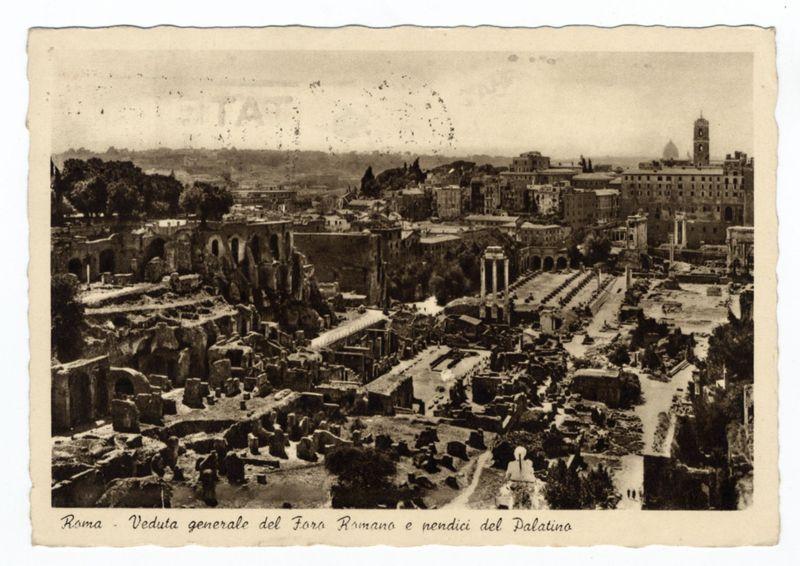 The image depicts an aerial view of ancient ruins, specifically the Roman Forum and the Palatine Hill in Rome. This black-and-white photograph appears to be vintage or historical, showcasing a wide expanse with various remains such as columns, arches, walls, and pathways indicative of classical architecture from antiquity.

In the foreground, there are scattered remnants that resemble broken stone structures, possibly parts of ancient buildings or monuments now reduced to rubble. The middle ground reveals more substantial architectural ruins including colonnades, large open spaces which may have been public squares in Roman times, as well as what looks like a bridge crossing over an archaeological site.

The background features the Palatine Hill with its distinctive terraced levels and scattered remains of buildings that could be related to the residence or seat of power for ancient Rome's emperors. Prominent structures stand out against the skyline including columns standing alone
