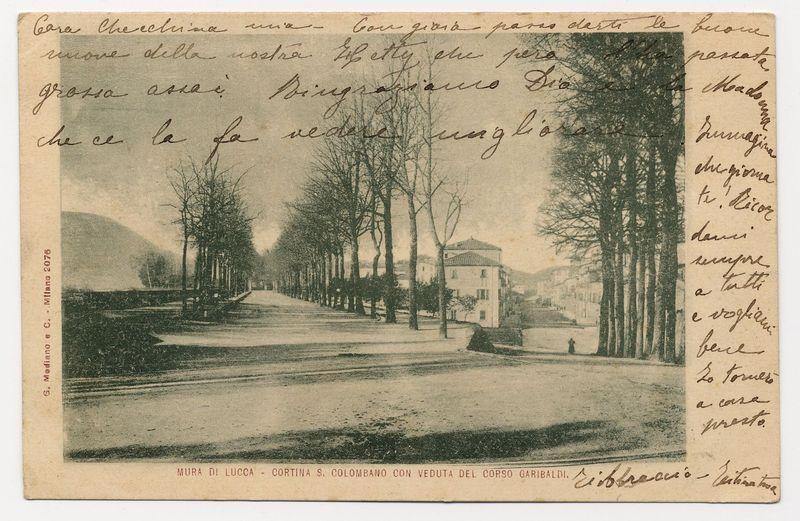 The image displays a vintage postcard depicting an outdoor scene. It appears to be from the late 19th or early 20th century, judging by its style and design. The card shows a wide road leading through what seems like a park with several leafless trees lining both sides. On one side of the road stands a line of buildings that could possibly be residential homes or small structures associated with the area's upkeep.

The upper part of the postcard has handwritten cursive text, which is not in English but appears to be Italian due to references such as "Cortina S. Colombano" and "Corso Garibaldi." The handwriting suggests personal correspondence rather than a formal message or announcement.

On the bottom right corner of the card, there's additional printed script that reads: 'MURA DI LUCCA - CORTINA S. COLOMBANO CON VEDUTA DEL CORSO GARIBALDI.' This text is indicative of the location and subject matter associated with this postcard—Lucca (Murad) in Lucca, Cortina San Colombano, and a