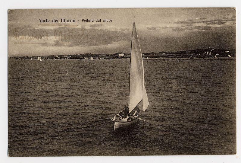 The image is a sepia-toned photograph depicting a serene seascape. In the foreground, there's a small sailboat with its sails fully unfurled, gently bobbing on calm waters under an overcast sky. The boat appears to be occupied by at least two individuals, one of whom seems to be handling the rigging or steering the vessel.

In the middle ground, several other sailing vessels are visible at various distances from the shore, suggesting a popular area for boating activities. On the horizon line, silhouettes and structures hint at landfall, with some buildings that could indicate residential areas or coastal establishments like restaurants or hotels. The text "Forte dei Marmi - Veduta dal mare" is prominently displayed across the top of the photograph in an elegant cursive font, identifying the location as Forte dei Marmi and indicating a viewpoint from the sea.

The overall mood conveyed by this image evokes tranquility and nostalgia, capturing a moment of leisurely sailing or boating