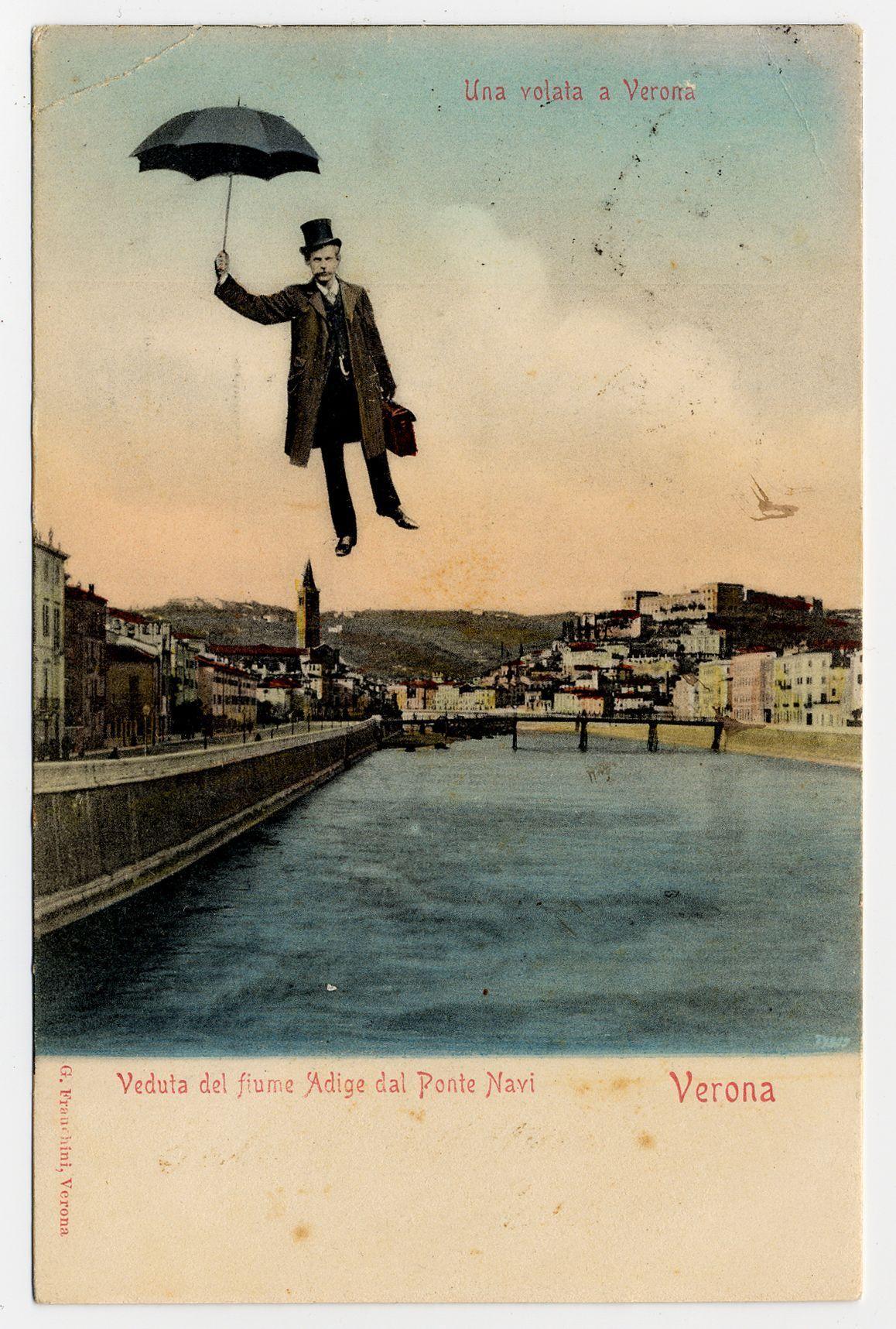 The image depicts a vintage postcard with an illustration of a man flying through the air, holding onto what appears to be his briefcase. He is dressed in early 20th-century attire: a long coat, top hat, and trousers, giving off a dapper appearance as he glides above a river that winds its way alongside buildings on both banks.

In the background, we see an impressionistic view of Verona with notable landmarks such as the Adige River flowing through. There's a bridge crossing over it and another structure resembling a tower or minaret can be seen rising prominently into the sky. The colors used in this part are softer compared to the foreground illustration; they blend warm earth tones like yellows, browns, and hints of pink with cooler greens for the river.

The postcard has text at its bottom which reads "Veduta del fiume Adige dal Ponto Navi Verona," indicating it is a view from the River Adige near the Bridge (possibly Ponte della Canonica) in Verona. Above this, there's anothe